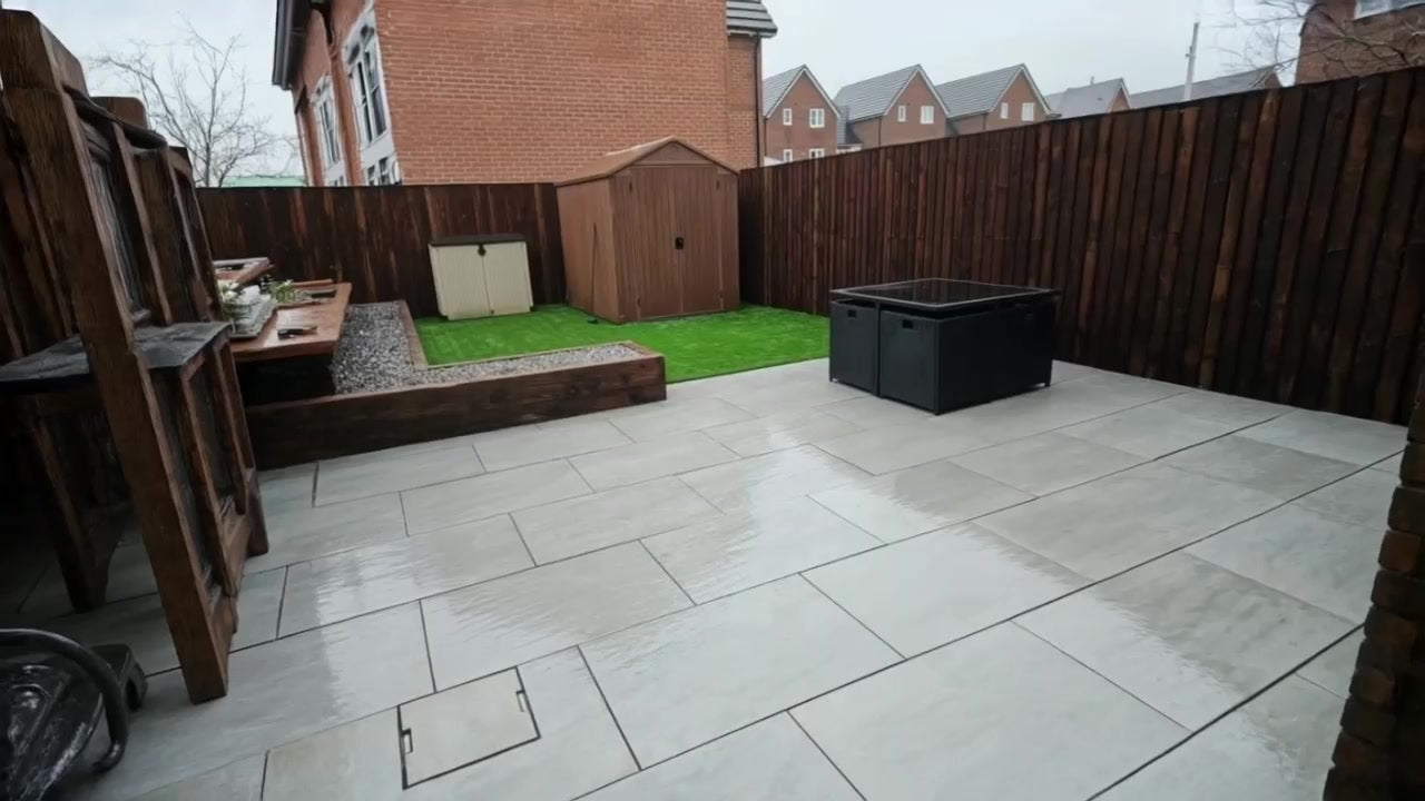 Garden patio with pale paving, raised beds and timber fencing